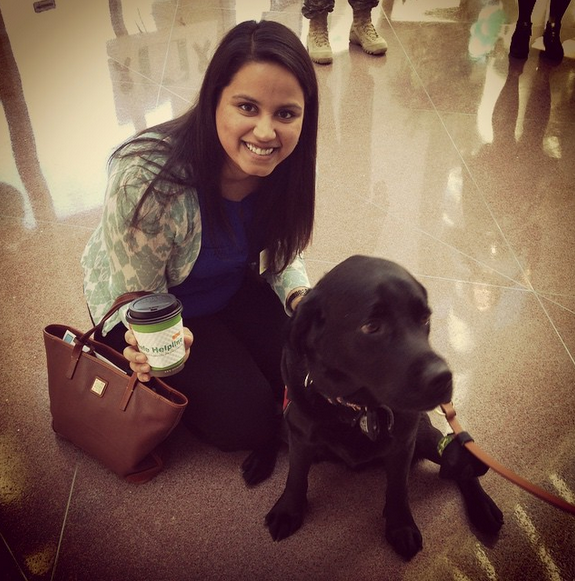 RAINN staffer Kinjal Dalal poses with a dog and a coffee cup with a DoD Safe Helpline sleeve.